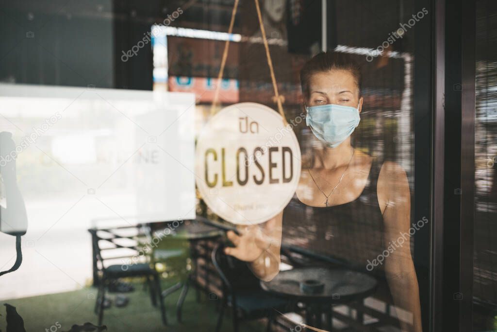 Store Owner woman in medical mask closed restaurant for quarantine
