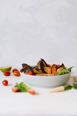 Humus tabağı ve beyaz arka planda sebzeler. Yan görünüm