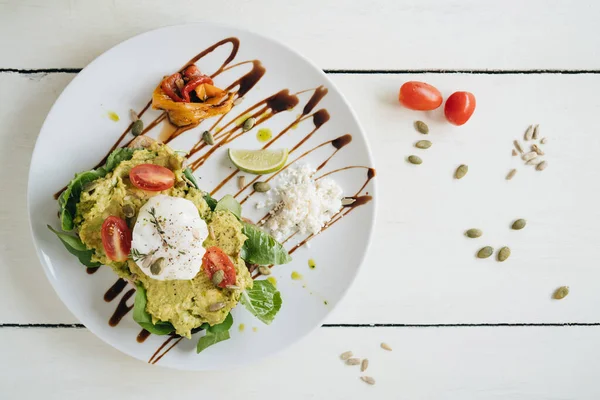 Sandwich Med Smadret Avocado Pocheret Med Tomater Den Hvide Tallerken - Stock-foto