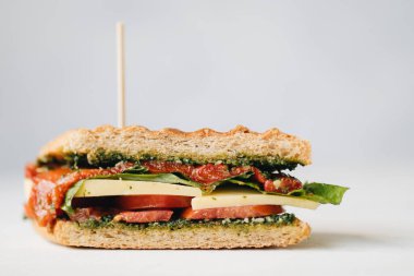 Kırmızı biberli panini ve beyaz arka planda beyaz tabakta pesto.