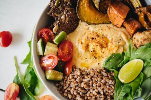 Тарелка с хумусом и овощами на белом фоне — стоковое фото