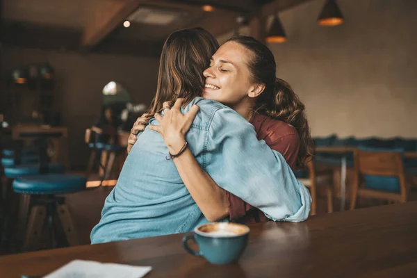 Jovem Feliz Abraçando Sua Melhor Amiga Sentada Café Tendo Uma — Fotografia de Stock