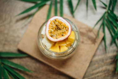 Tahta arka planda yoğurt ve tropikal meyveli müsli.