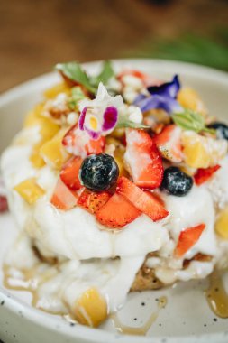 Kremalı krep ve tahta bir masada beyaz tabakta meyve. Yakın çekim görünümü