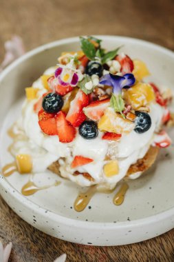 Kremalı krep ve tahta bir masada beyaz tabakta meyve. Yakın çekim görünümü