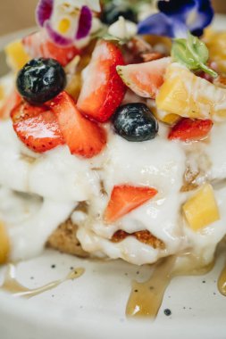 Kremalı krep ve tahta bir masada beyaz tabakta meyve. Yakın çekim görünümü