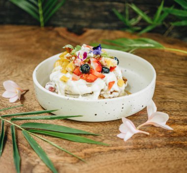 Kremalı krep ve tahta bir masada beyaz tabakta meyve. Yan görünüm