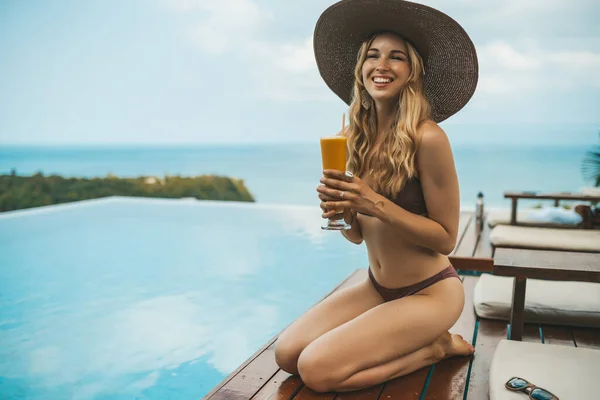 Lächelnde Blonde Frau Mit Sommermütze Sitzt Swimmingpool Und Trinkt Mango — Stockfoto