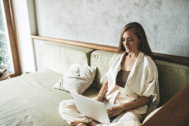 Kanepede bilgisayar başında çalışan bir kadın. Boşluğu kopyala