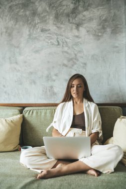 Kanepede bilgisayar başında çalışan bir kadın. Boşluğu kopyala