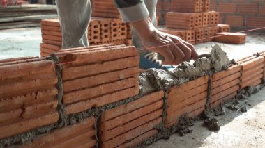 Duvarcı işçisi dış duvara tuğla döşüyordu.