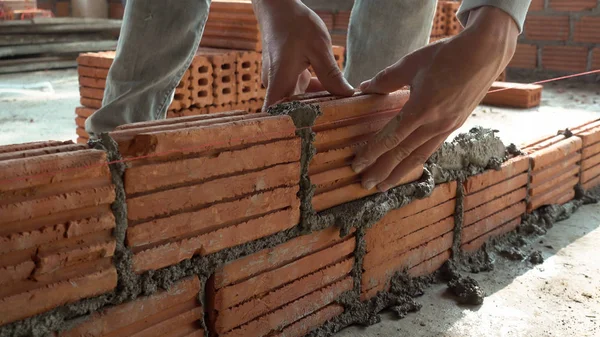 Robotnik murarski montujący ceglany mur na ścianach zewnętrznych — Zdjęcie stockowe