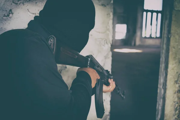 Terrorista em uniforme preto e máscara com kalashnikov — Fotografia de Stock
