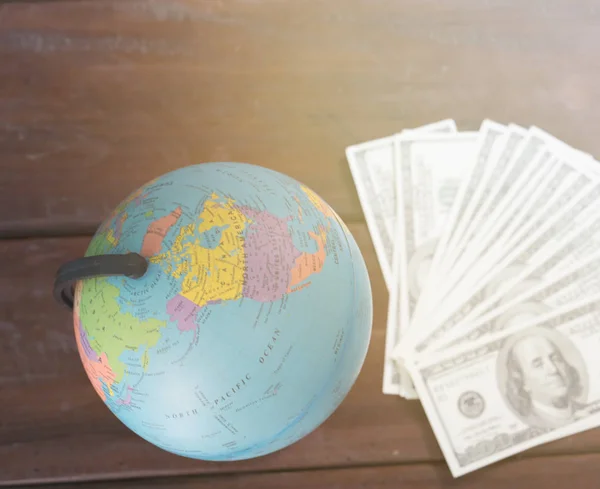 Wereldbol met dollarbiljet op tafel — Stockfoto
