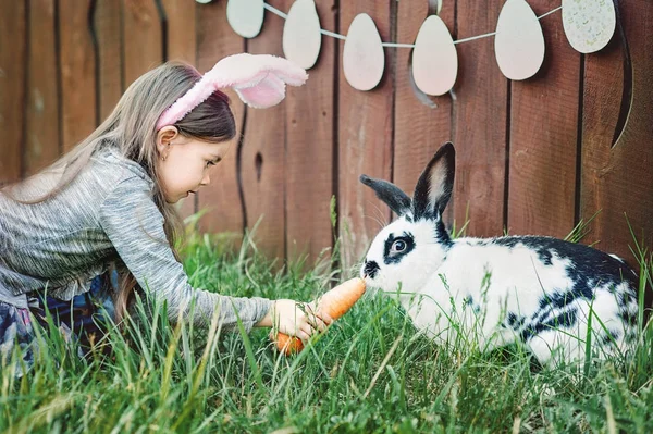 Girl feeding rabbit with carrot.