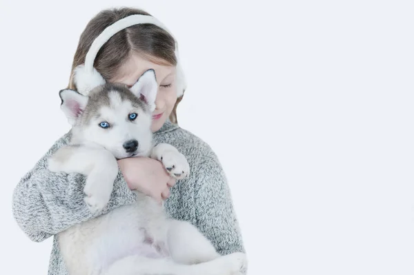 Маленькая девочка обнимает щенка Хаски — стоковое фото
