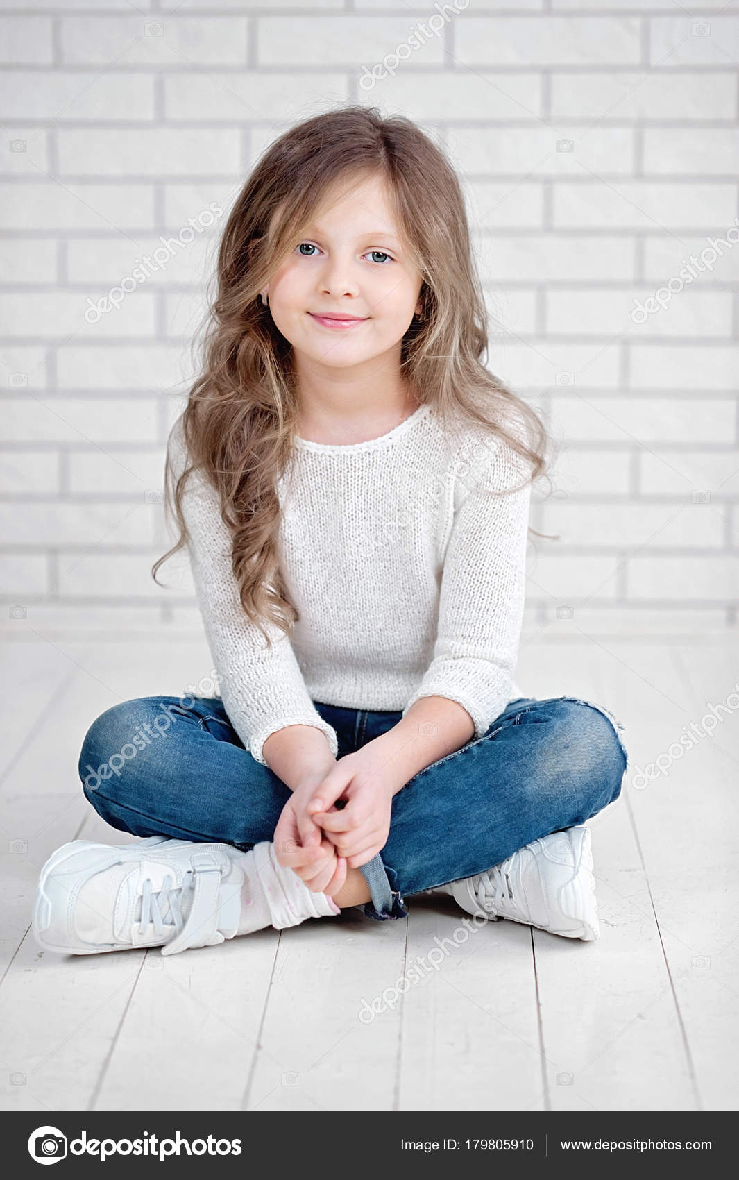 Portrait de mignonne petite fille de 7 ans souriante et assise sur le  plancher de bois blanc en studio image libre de droit par serenko_nata ©  #179805910