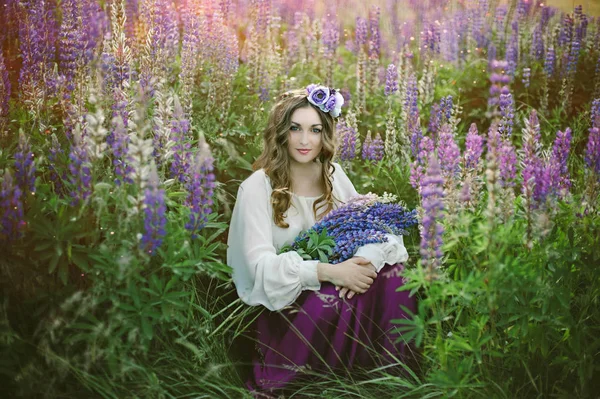 フィールド上夕暮れルピナスの花束を持ってウルトラ バイオレットと白のドレスの美しい若い女性 自然とロマンのコンセプト — ストック写真