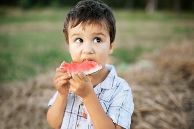 sevimli çocuk yeşil sahada karpuz yeme. Yaz ruh hali.