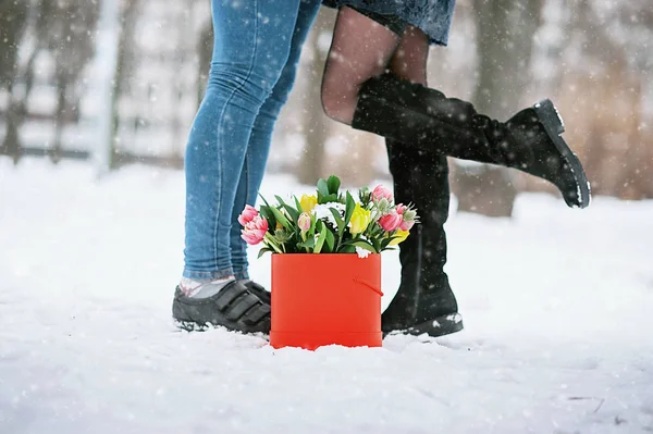 Мужчина держит красную подарочную коробку с красивым букетом цветущих розовых, желтых и белых тюльпанов и белых хризантем с зелеными листьями, на открытом воздухе — стоковое фото