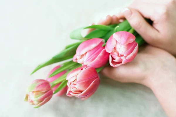 Close-up tangan penjual bunga dengan bunga. Florist memegang buket bunga mekar tulip merah muda pada latar belakang linen . — Stok Foto