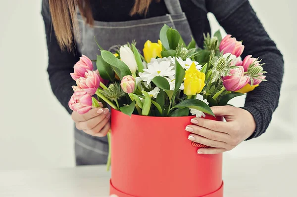 Close-up hands of florist with flowers. Florist holding blooming bouquet of pink tulips on a linen background.