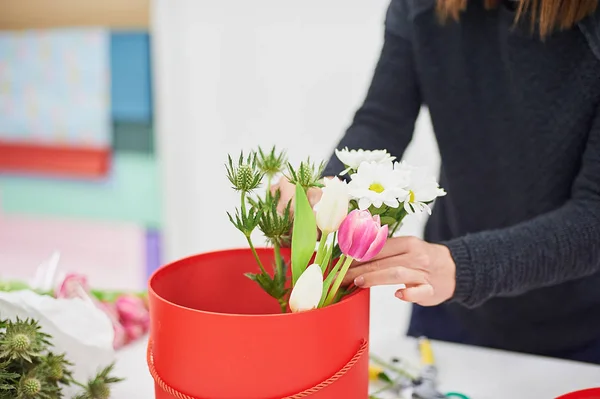 Close-up hands of florist with flowers. Florist holding blooming bouquet of pink tulips on a linen background.