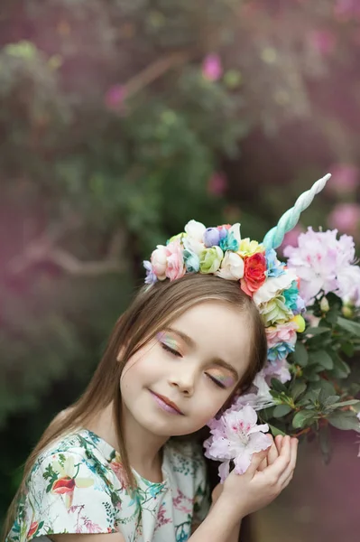Fantasy little girl with rainbow unicorn horn with flowers in azalea park — Stock Photo, Image