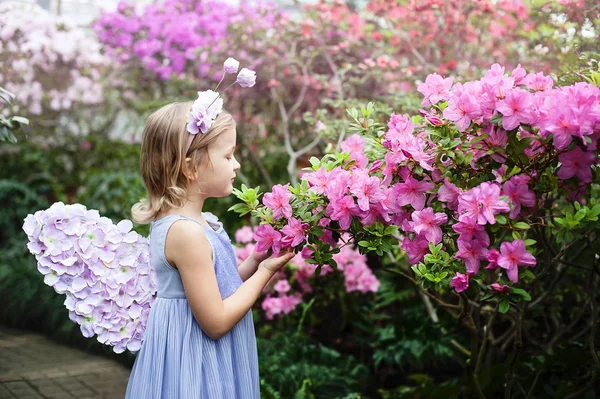 Girl sniffing flowers of azaleas. flowering azaleas in the park — Stock Photo, Image