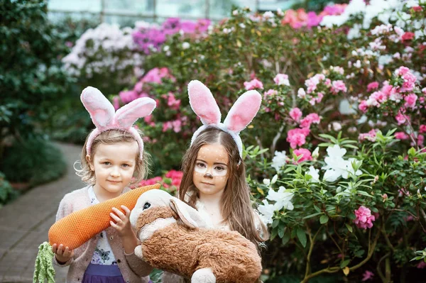 Children play with toy rabbit. Laughing child at Easter egg hunt with pet bunny. Little toddler girl playing with animal in the garden. — Stock Photo, Image