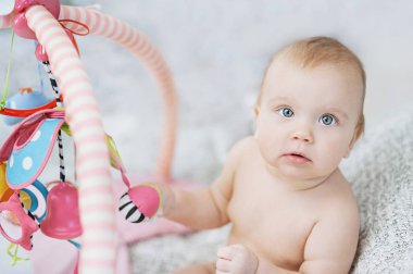 Bebek gelişmekte olan halıya yalan. Mobil olarak oynuyor. eğitici oyuncaklar. Tatlı çocuk kaynıyor ve iskambil ile oyuncaklar üzerinde halı
