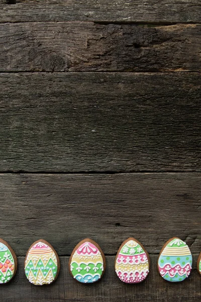 Lebkuchen in Form von bunten Eiern auf dunklem Holzgrund. — Stockfoto