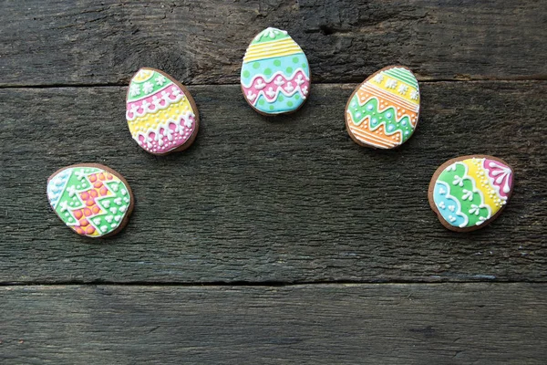 Lebkuchen in Form von bunten Eiern auf dunklem Holzgrund. — Stockfoto