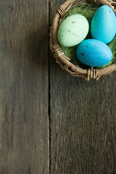 Пасхальные яйца в корзине на деревянном фоне — стоковое фото