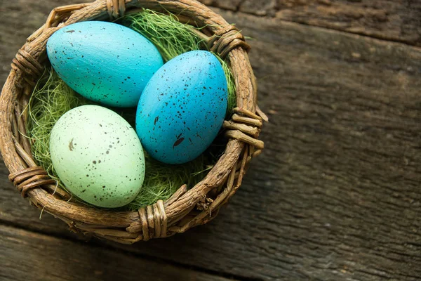 Пасхальные яйца в корзине на деревянном фоне — стоковое фото
