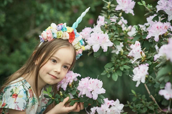 Fantasy little girl with rainbow unicorn horn with flowers in azalea park. for Halloween — Stock Photo, Image