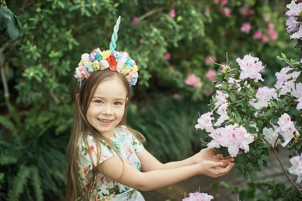 Fantasy little girl with rainbow unicorn horn with flowers in azalea park — Stock Photo, Image