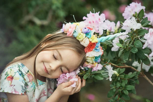 Fantasy little girl with rainbow unicorn horn with flowers in azalea park — Stock Photo, Image