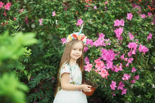 Fantasy little girl with rainbow unicorn horn with flowers in azalea park — Stock Photo, Image