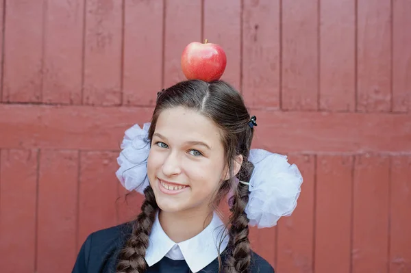 Ευτυχισμένος Σχολείο Κορίτσι Στέκεται Κόκκινο Μήλο Στο Κεφάλι Ενάντια Ξύλινο — Φωτογραφία Αρχείου