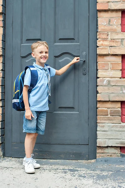 First-grader with a backpack is at the door of the school. the first call. end of the school year. hunger for knowledge. — Stock Photo, Image