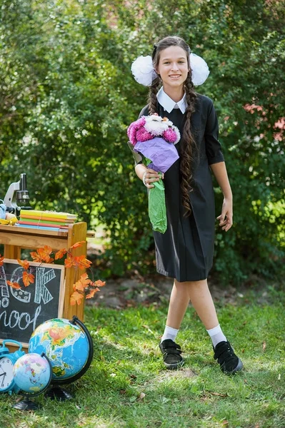 Portrait of a beautiful young schoolgirl with red apple on books in a festive school uniform — Stock Photo, Image