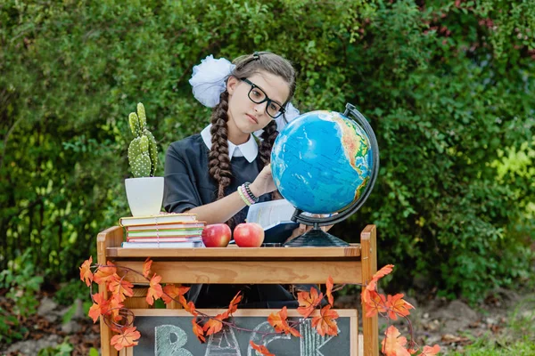 Portrait of a beautiful young schoolgirl sitting at a desk — Stock Photo, Image