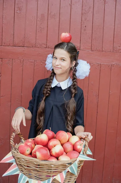 Portrait of a schoolgirl standing with apple on head — Stock Photo, Image
