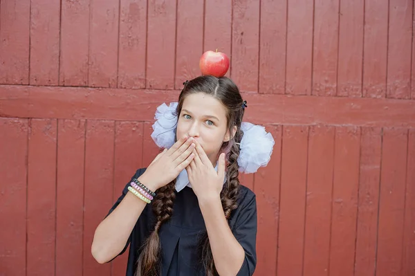 Porträt einer Schülerin, die mit einem Apfel auf dem Kopf steht — Stockfoto