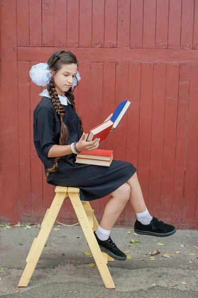 Μαθήτρια με βιβλία κάθεται σε μια κίτρινη Σκάλα — Φωτογραφία Αρχείου
