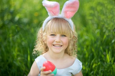 Paskalya yumurtaları ve yeşil Bahçe, tavşan kulakları ile şirin komik kız. Paskalya kavramı. 