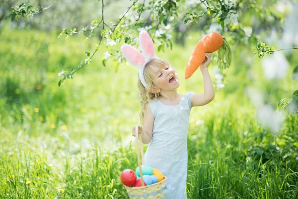 Смішна Дівчина Великодніми Яйцями Вухами Кролика Їсть Гігантську Іграшку Морквини — стокове фото