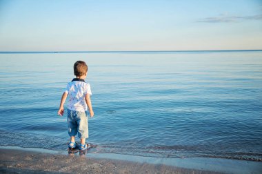 küçük çocuk deniz tarafından suda taş atar. Mutlu çocukluk. yaz tatili