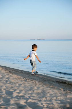 küçük çocuk deniz tarafından suda taş atar. Mutlu çocukluk. yaz tatili